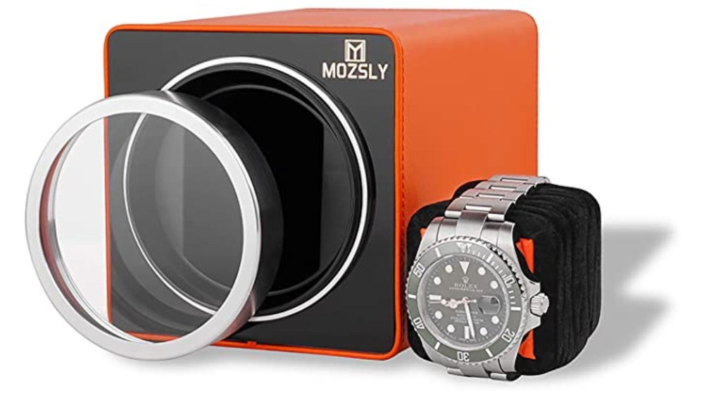 An orange and black watch winder box with glass front removed and pillow displayed.