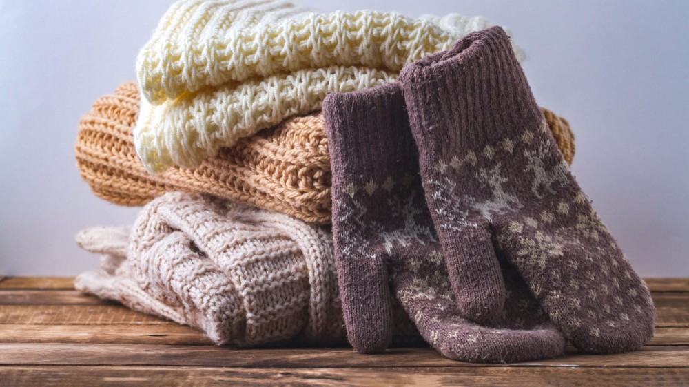 A stack of warm winter scarves and a pair of mittens.