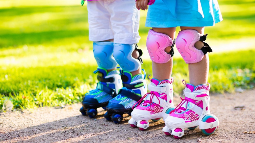 Girl and boy learn to roller skate in summer park.