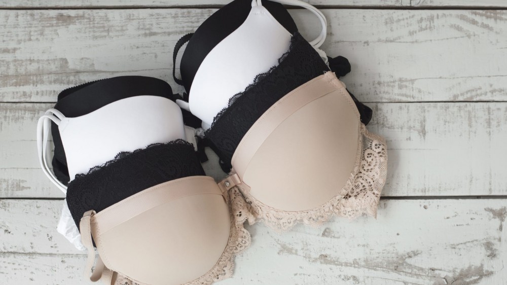 beige, black, and white bras lined up on a table.