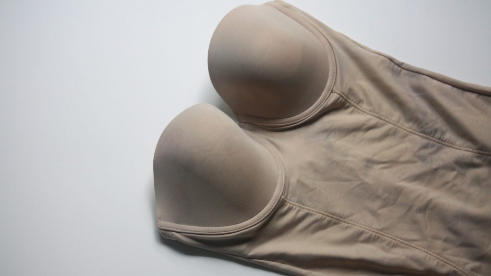 A beige shaping bodysuit with a built-in bra.