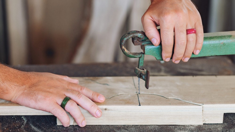 Male hands of a European guy with silicone rings working on a wood milling machine.