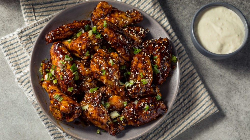 Plate of chicken wings topped with chili crisp, green onions, and sesame seeds