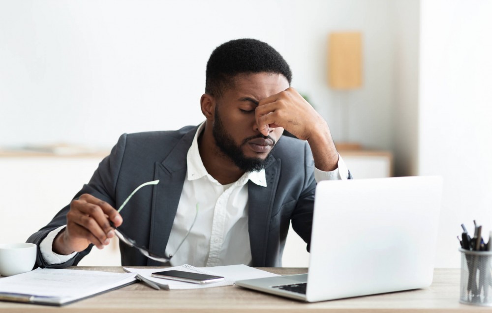 Stressed man at work, suffering from headache at office